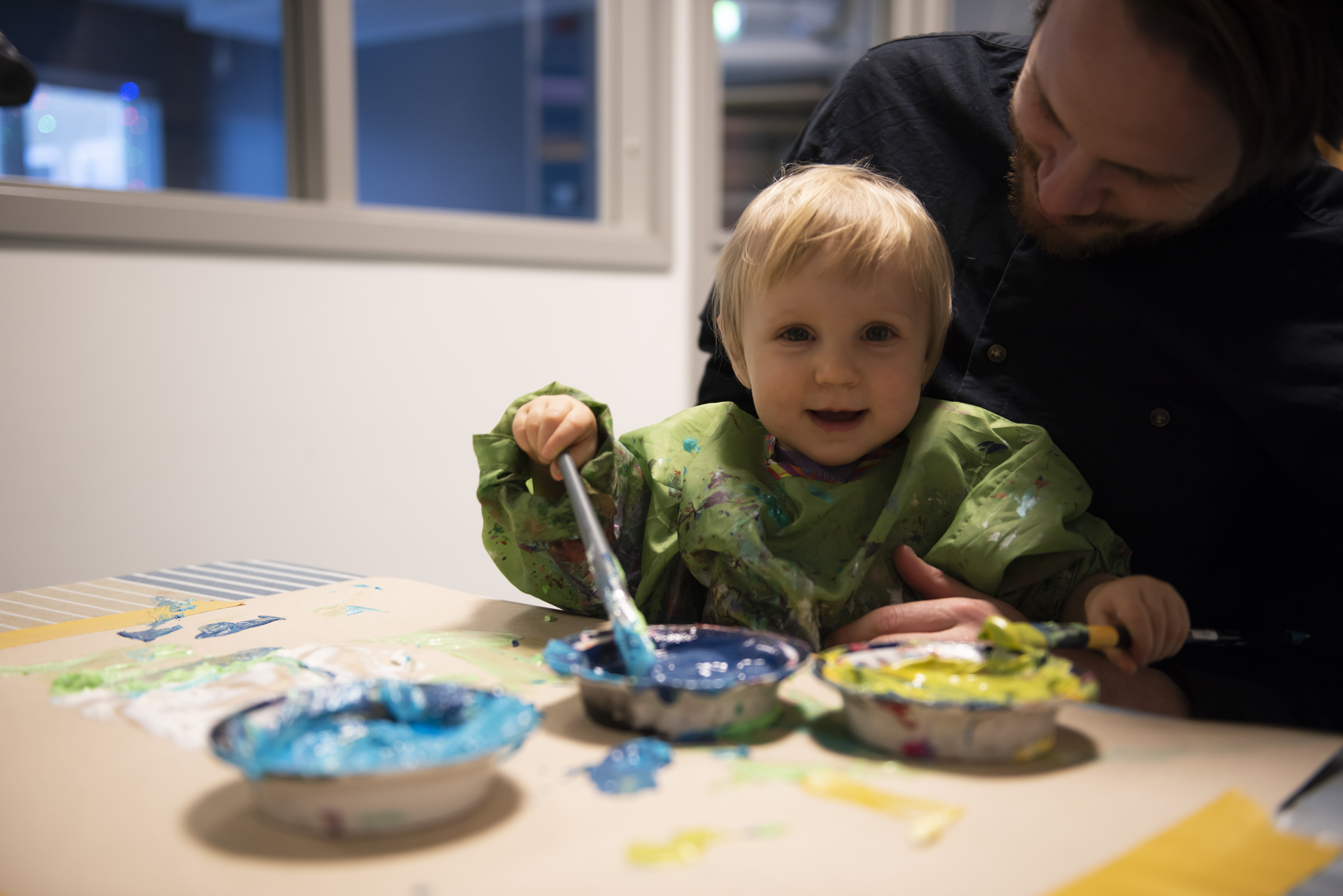Ett barn som målar tillsammans med en vuxen. 