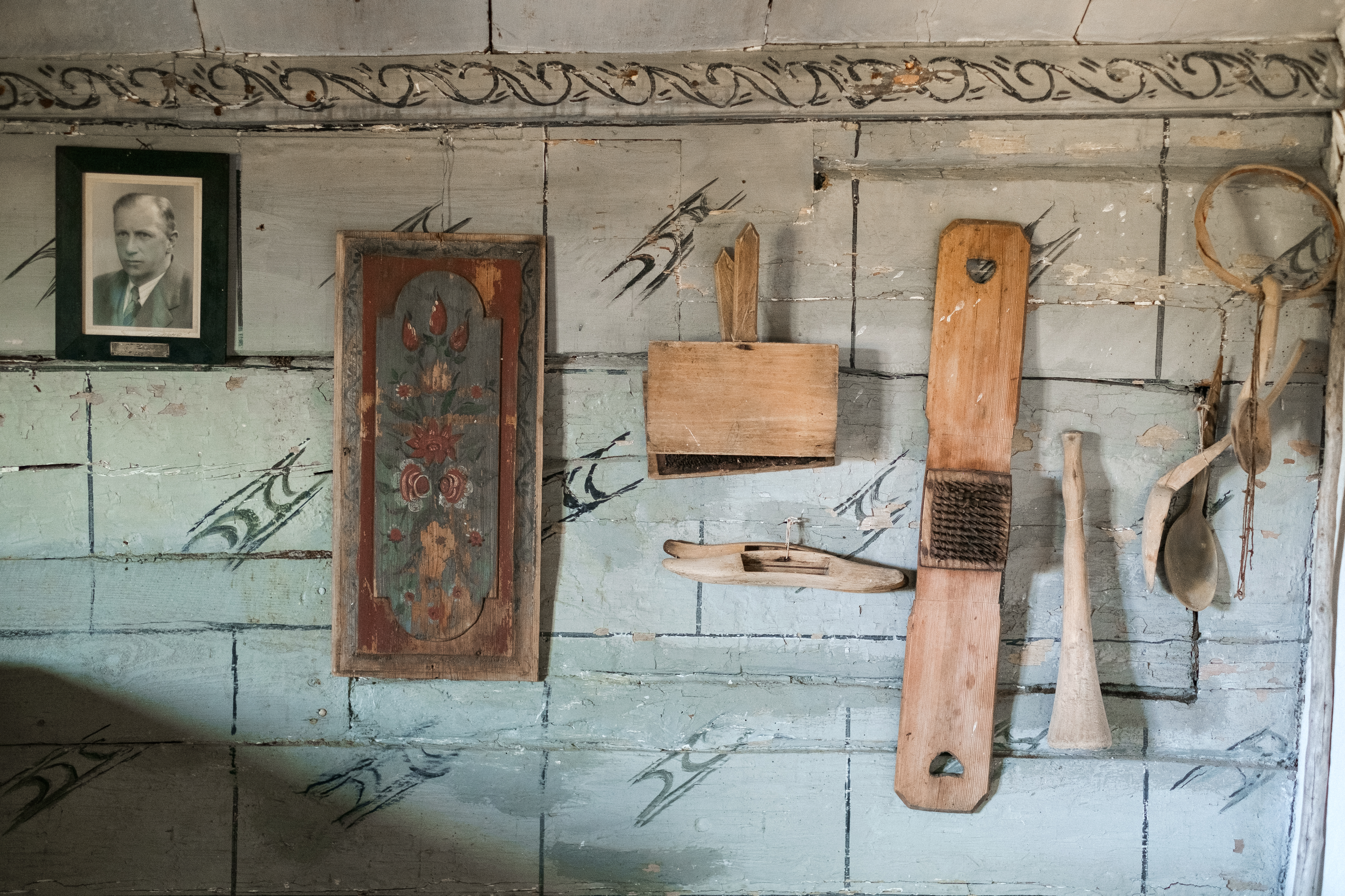 Närbild på vägg med olika redskap och en tavla