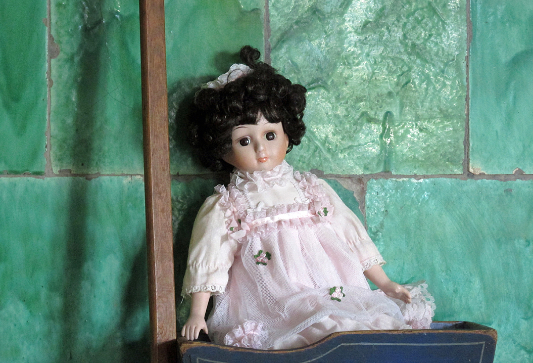 Docka mot bakgrund av grön kakelugn i Fillinge tingshus.