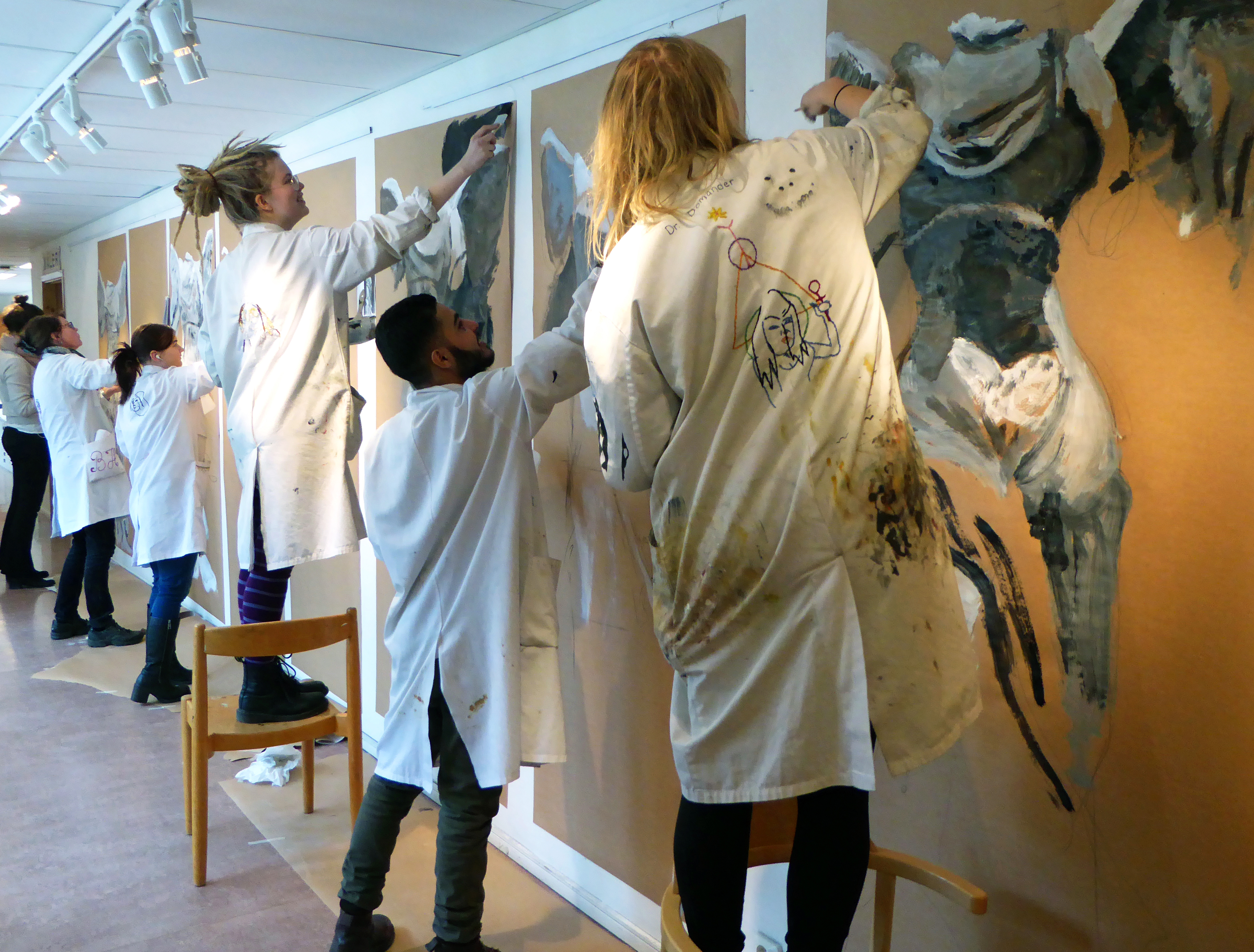 Elever på en konstskola målar var sitt verk på en vägg i en korridor.