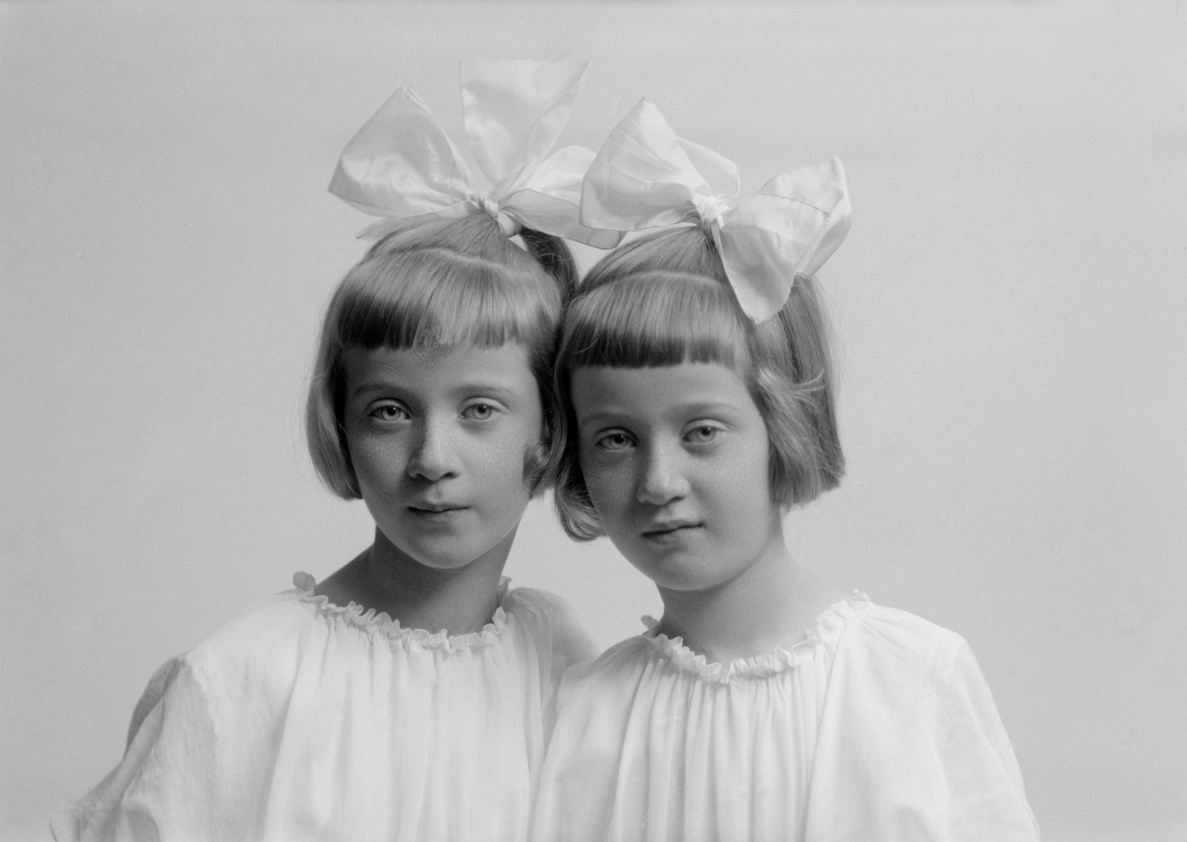 Två kavata flickor poserar i Maria Teschs ateljé i Linköping något år in på 1920-talet. Birgit och Inger är deras namn och de är tvillingdöttrar till bataljonsläkaren Gunnar Cars och dennes hustru Elsa. Från glasnegativ OM.TE.001577