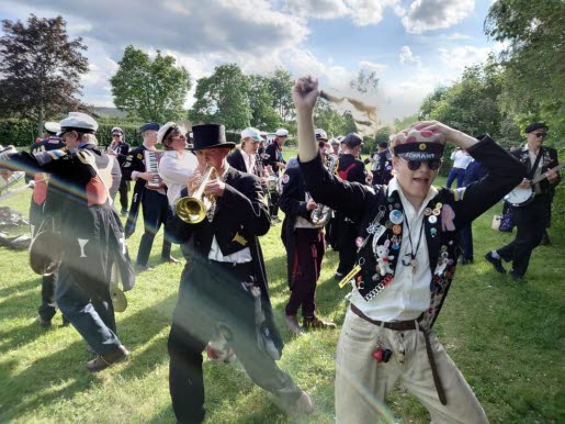 Bonnkapälle spelar utomhus, grönt gräs och sommarmoln