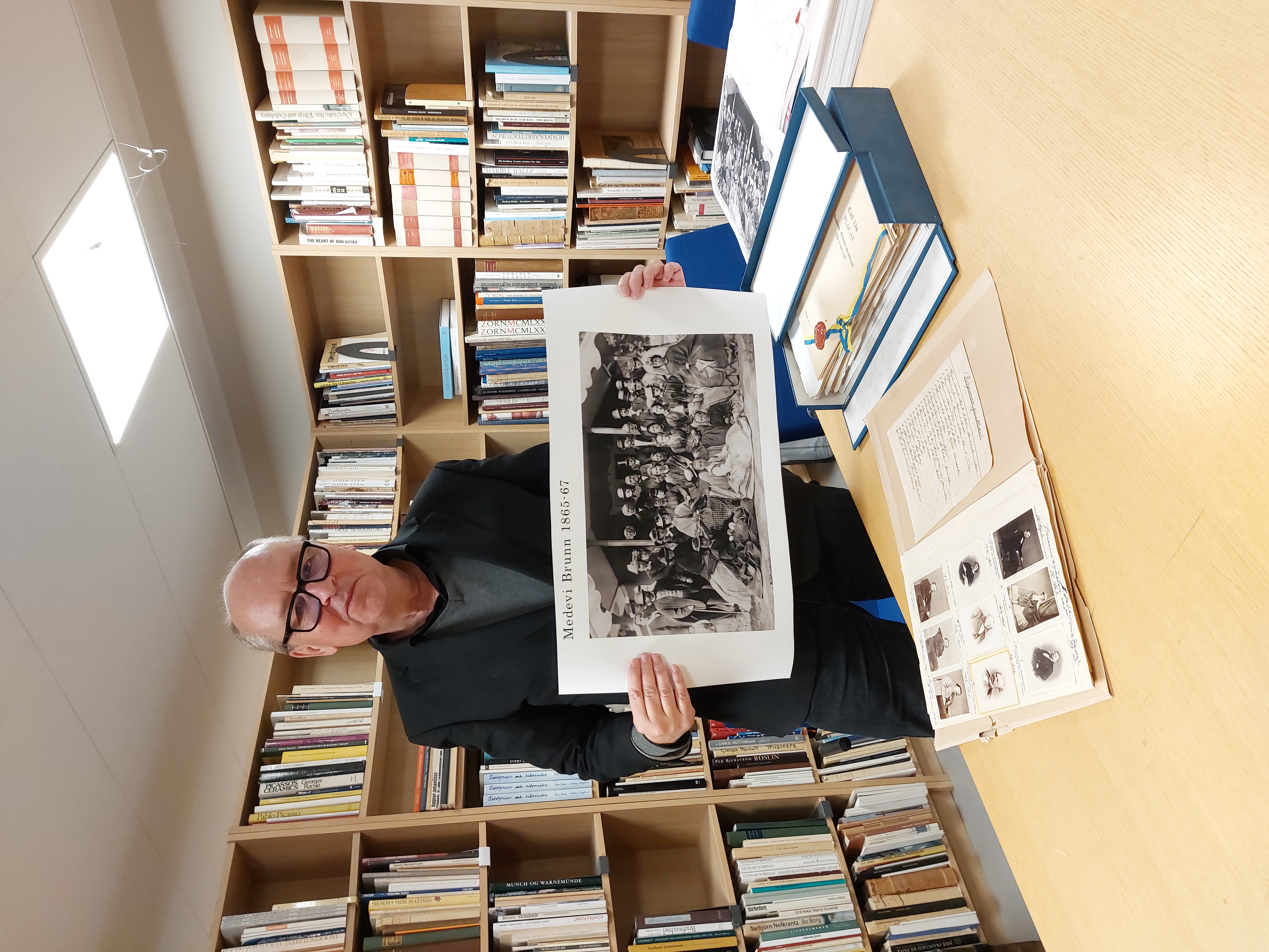 Arkivarie Jim Löfgren visar 1860-talsfotografier från Medevi brunn i Östergötlands museums arkiv och bibliotek.