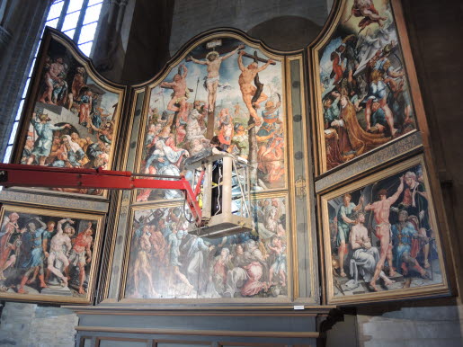 Konservator Johanna Roos på arbete i hög höjd i en kyrka.