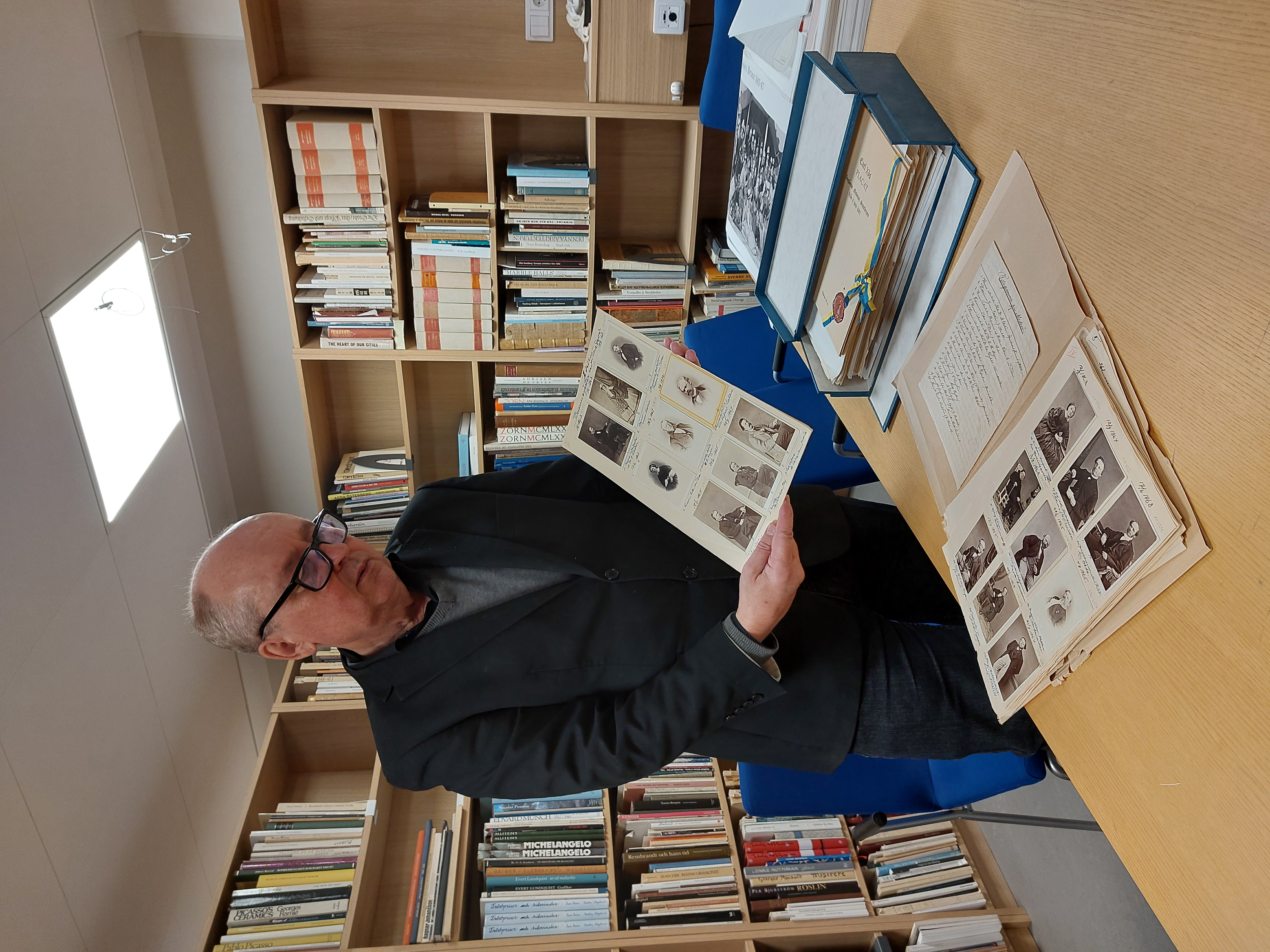 Arkivarie Jim Löfgren visar 1860-talsfotografier från Medevi brunn i Östergötlands museums arkiv och bibliotek.