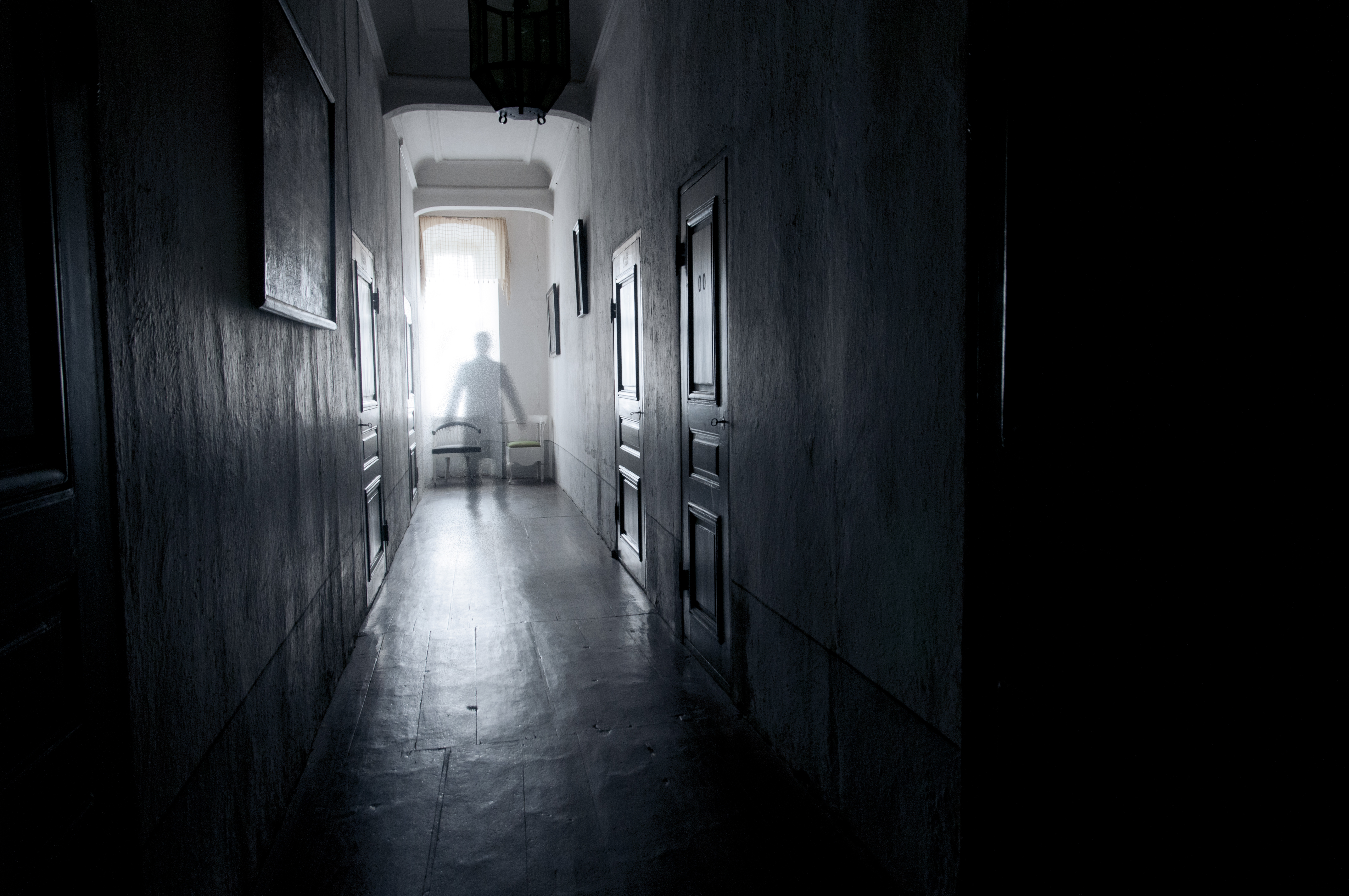 Ett svartvitt fotografi av en korridor där en spöklik gestalt visar sig.