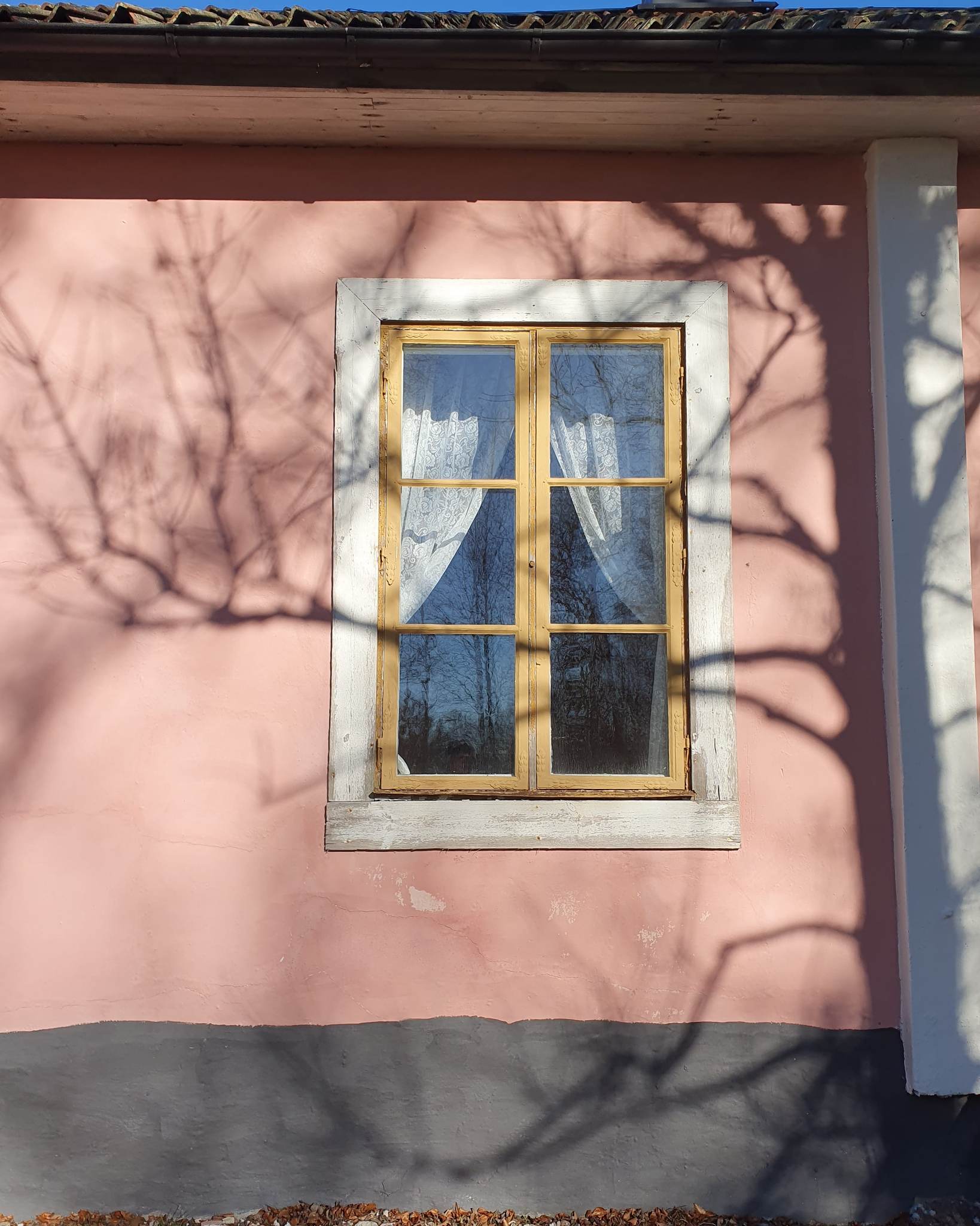 Ett gulmålat fönster på en äldre rosa fasad.